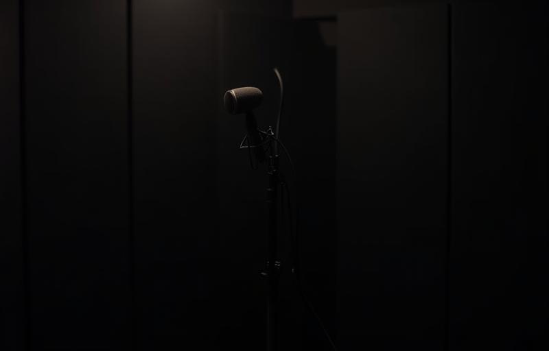 Small isolated vocal recording booth with a high-quality microphone set up on a stand